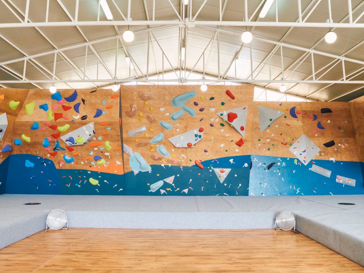 Muro boulder con prese colorate e materassoni nella palestra di arrampicata Double Dyno a Cagliari
